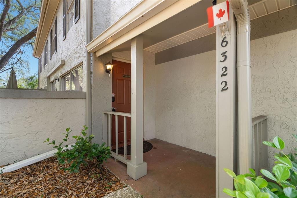 A covered entryway features a brown door, a small porch, and house numbers on a post — 6322 TREETOP CIRCLE, TEMPLE TERRACE, FL