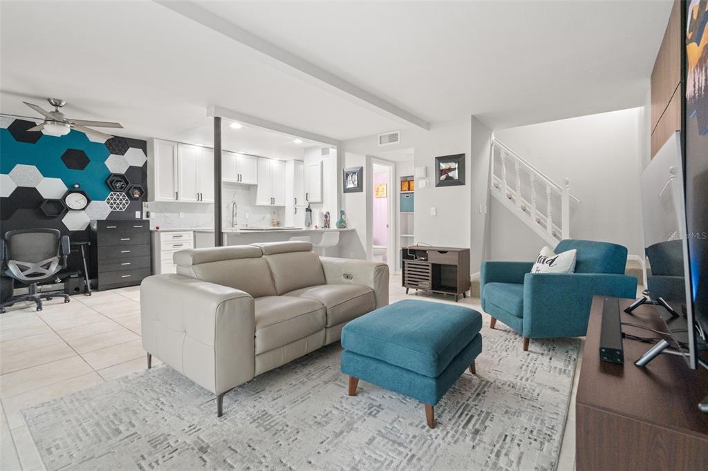 A living room with a beige sofa, blue armchair, and an open kitchen in the background — 6322 TREETOP CIRCLE, TEMPLE TERRACE, FL