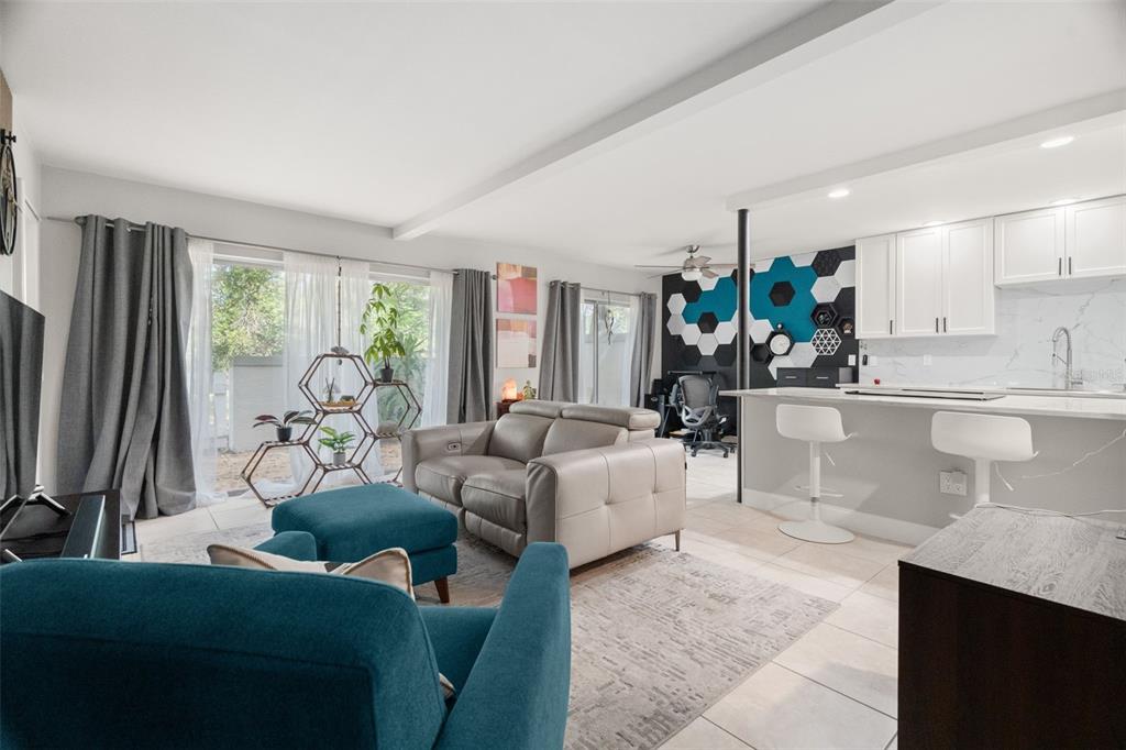An open-concept living room and kitchen featuring a teal accent wall and modern furniture — 6322 TREETOP CIRCLE, TEMPLE TERRACE, FL