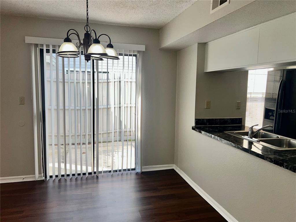 A dining area with dark wood flooring, a chandelier, and a sliding glass door — 2807 RIO GRANDE TRAIL UNIT 2807, KISSIMMEE, FL