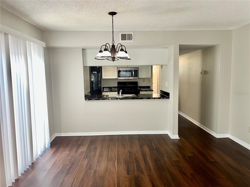 A dining area with wood-look flooring, a chandelier, and a pass-through window to the kitchen — 2807 RIO GRANDE TRAIL UNIT 2807, KISSIMMEE, FL