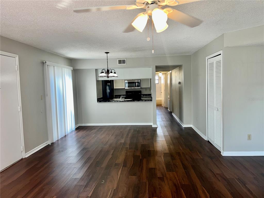 An open-concept living area features dark wood flooring, a ceiling fan, and a pass-through kitchen — 2807 RIO GRANDE TRAIL UNIT 2807, KISSIMMEE, FL
