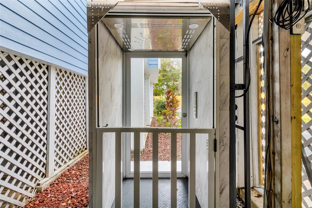 An outdoor residential elevator with a metal gate and marble-patterned walls stands beside a house — 11961 W EDGEVIEW COURT UNIT 11961, CRYSTAL RIVER, FL
