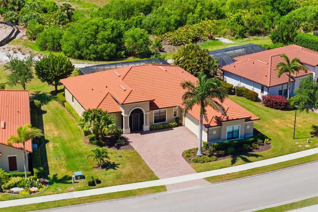 An aerial view of a single-story house with a red tile roof and paved driveway — 10730 IRONBRIDGE DRIVE, VENICE, FL