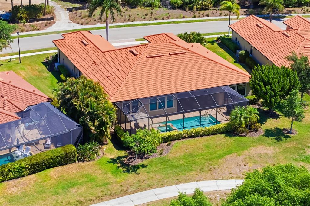 An aerial view of a house with a tiled roof, screened pool, and surrounding lawn — 10730 IRONBRIDGE DRIVE, VENICE, FL