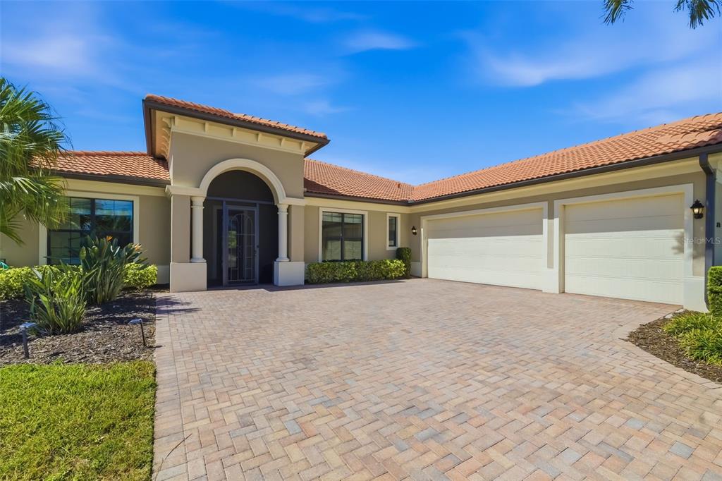 A single-story house with a tiled roof, arched entryway, and a two-car garage — 10730 IRONBRIDGE DRIVE, VENICE, FL
