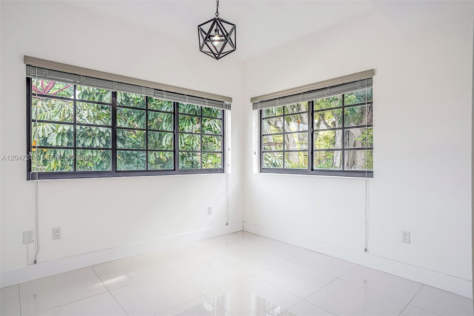 A bright, empty room features white walls, tiled floors, large windows, and a geometric pendant light — 1901 S Le Jeune Rd # 2, Coral Gables FL 33134, CORAL GABLES, FL