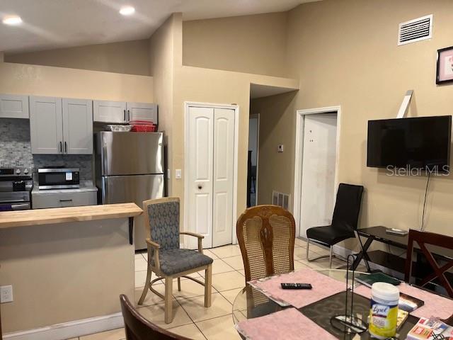 A kitchen with gray cabinets and stainless steel appliances opens into a dining area — 4001 KALUGA PARK STREET, ORLANDO, FL