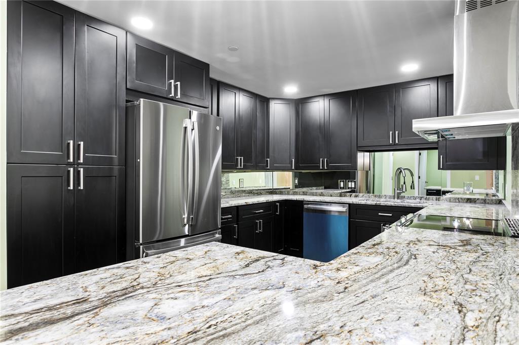 A kitchen with dark cabinets, stainless steel appliances, granite countertops, and a mirrored backsplash — 1 BEACH DRIVE SE UNIT 1112, ST PETERSBURG, FL
