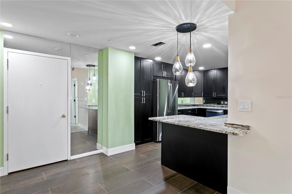 A kitchen features black cabinets, stainless steel appliances, and light-colored granite countertops — 1 BEACH DRIVE SE UNIT 1112, ST PETERSBURG, FL