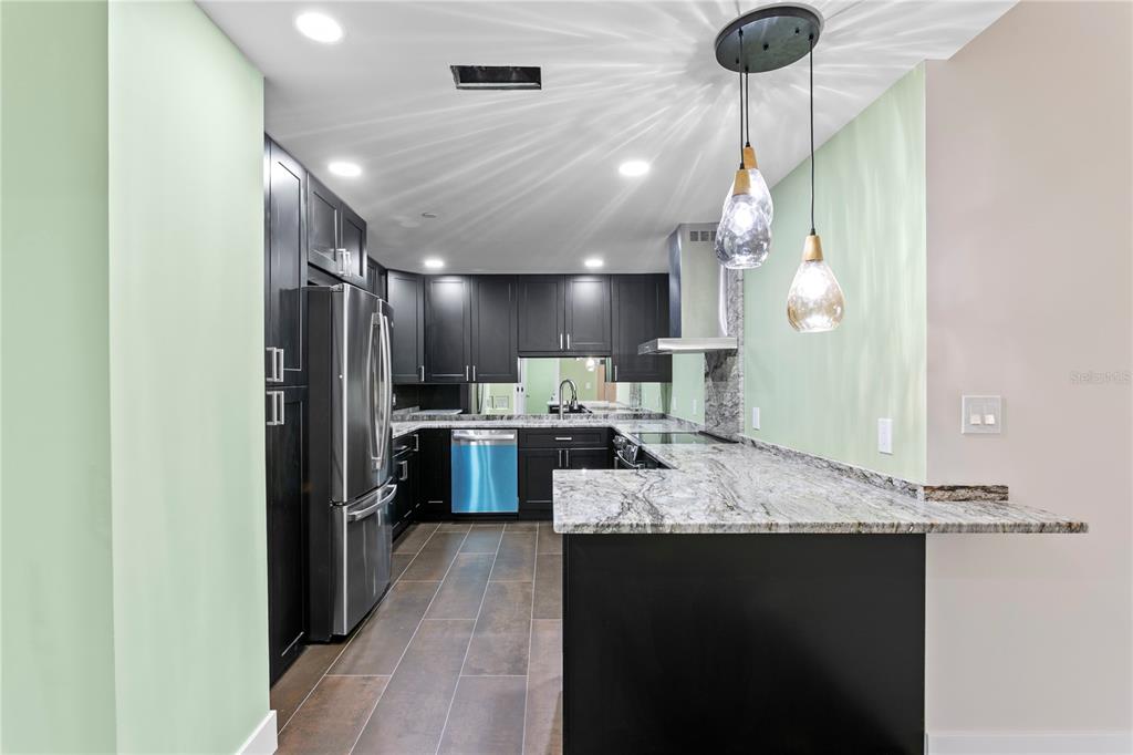 A kitchen features dark cabinets, granite countertops, a breakfast bar, and a mirrored wall — 1 BEACH DRIVE SE UNIT 1112, ST PETERSBURG, FL