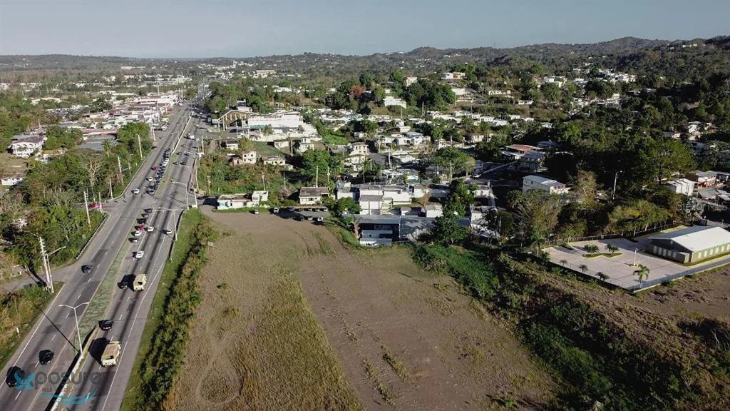 An aerial view shows a large, undeveloped grassy lot adjacent to a multi-lane highway — 0 CARR DM #2-166.6, HORMIGUEROS, PR