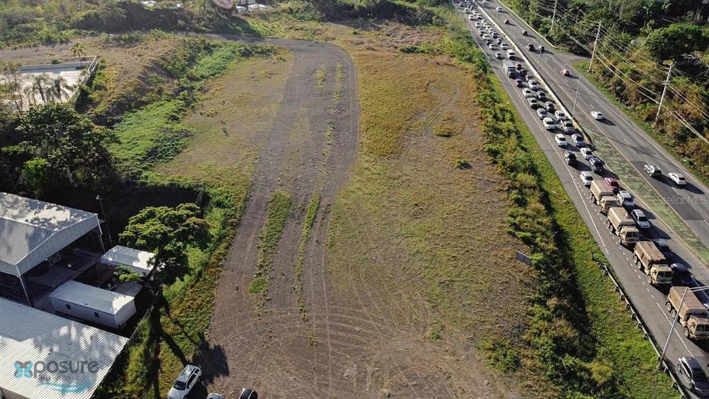 An aerial view shows a vacant, grassy lot adjacent to a busy highway — 0 CARR DM #2-166.6, HORMIGUEROS, PR
