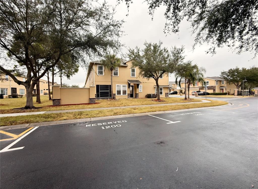 A two-story tan stucco building sits behind a parking lot with reserved spaces — 1200 TETON DRIVE, KISSIMMEE, FL