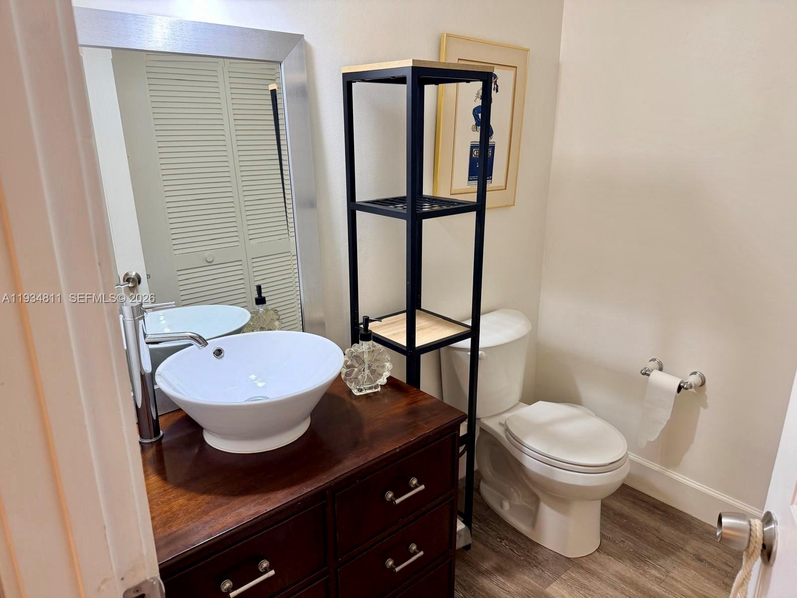 A bathroom features a vessel sink on a wooden vanity, a tall shelf, and a toilet — 55 Ocean Lane Dr # 1030, Key Biscayne FL 33149, KEY BISCAYNE, FL