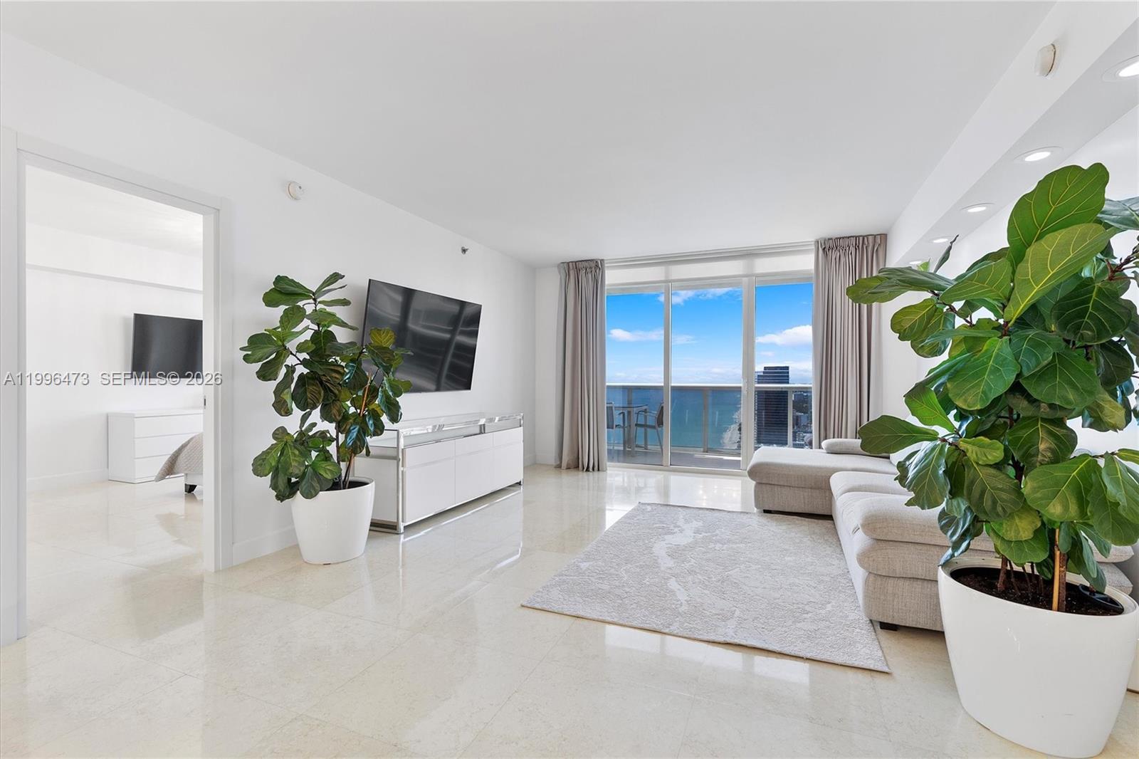 A bright living room features white tile floors, a sectional sofa, and floor-to-ceiling balcony windows — 1830 S Ocean Dr # 4503, Hallandale Beach FL 33009, HALLANDALE BEACH, FL