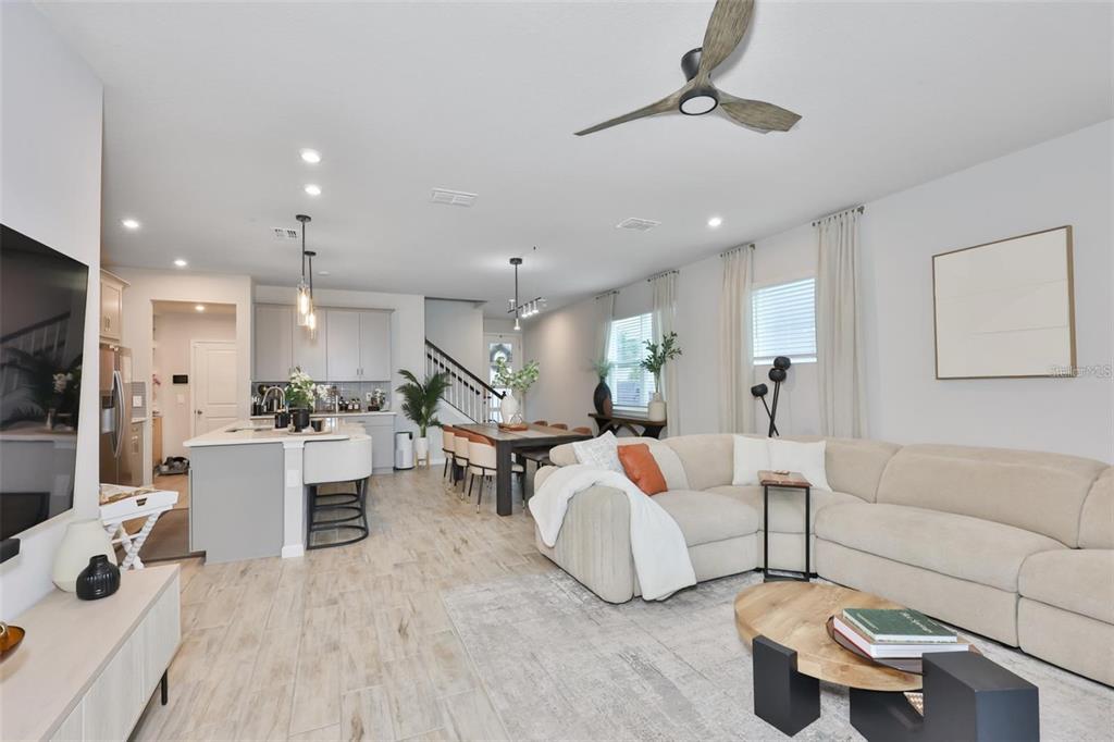 An open-concept living room and kitchen feature light wood flooring and a beige sectional sofa — 1123 CREEK VALLEY COURT, BRANDON, FL