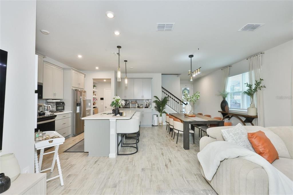 An open-concept kitchen and dining area features light gray cabinetry, a central island, and tile flooring — 1123 CREEK VALLEY COURT, BRANDON, FL