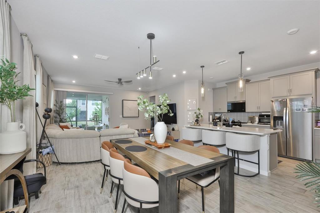 An open-concept dining area and kitchen feature a wooden table, island seating, and tile flooring — 1123 CREEK VALLEY COURT, BRANDON, FL
