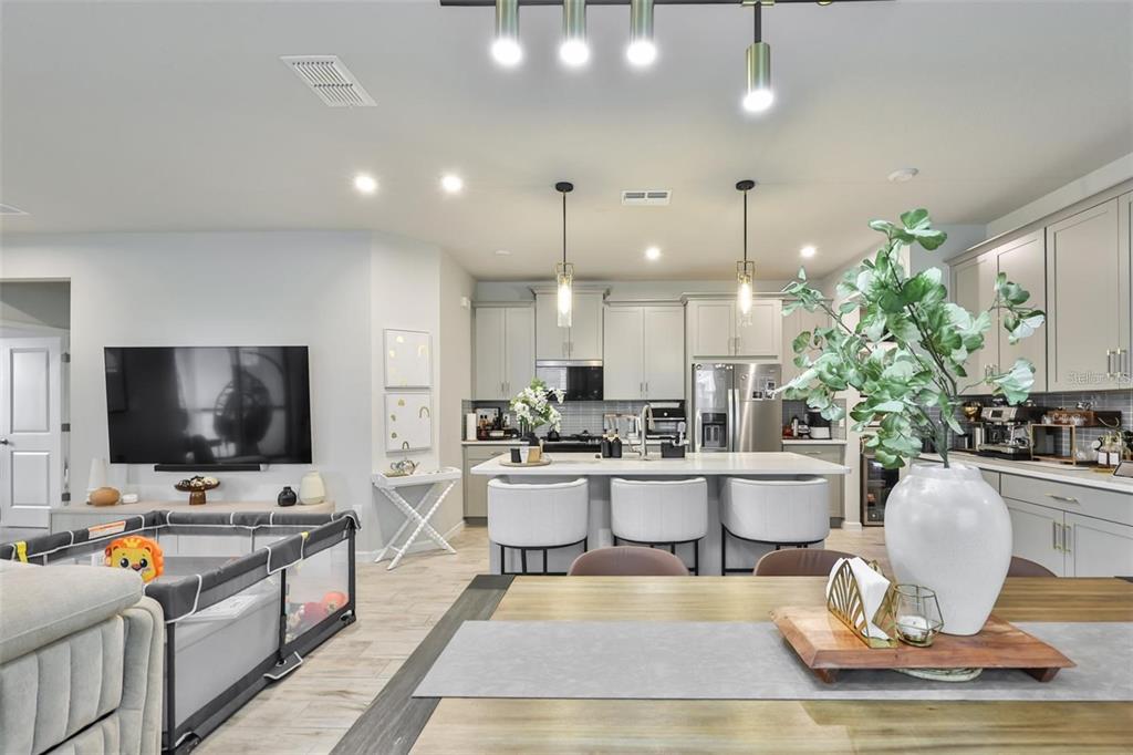 An open-concept kitchen and living area features a central island, light cabinetry, and wood flooring — 1123 CREEK VALLEY COURT, BRANDON, FL