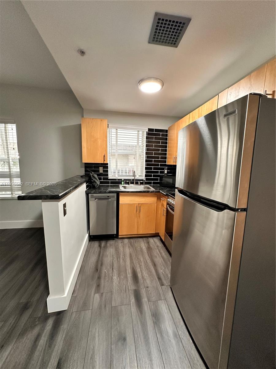 A kitchen features stainless steel appliances, light wood cabinets, and a black subway tile backsplash — 1542 Drexel Ave # 107, Miami Beach FL 33139, MIAMI BEACH, FL