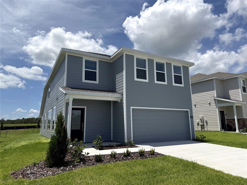 A two-story gray house features a front-facing garage, a covered entryway, and a concrete driveway — 3035 GRANITE RIDGE AVENUE, MINNEOLA, FL
