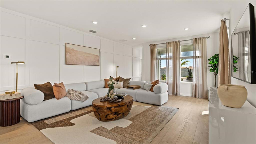 A living room features a white sectional sofa, a wooden coffee table, and paneled walls — 3035 GRANITE RIDGE AVENUE, MINNEOLA, FL
