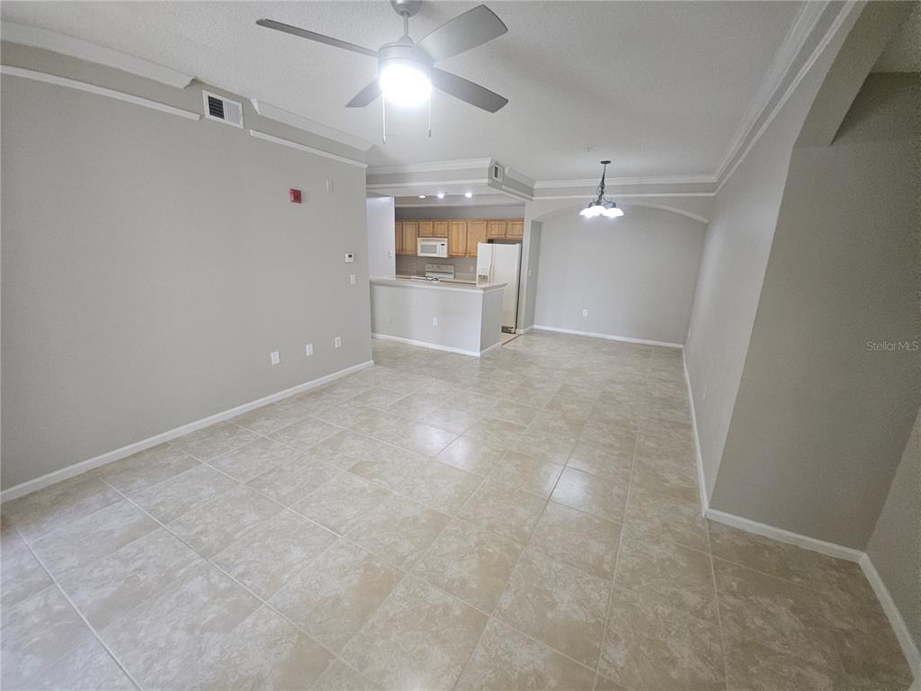 An open-concept living and dining area features light tile flooring and a ceiling fan — 12024 VILLANOVA DRIVE UNIT 103, ORLANDO, FL