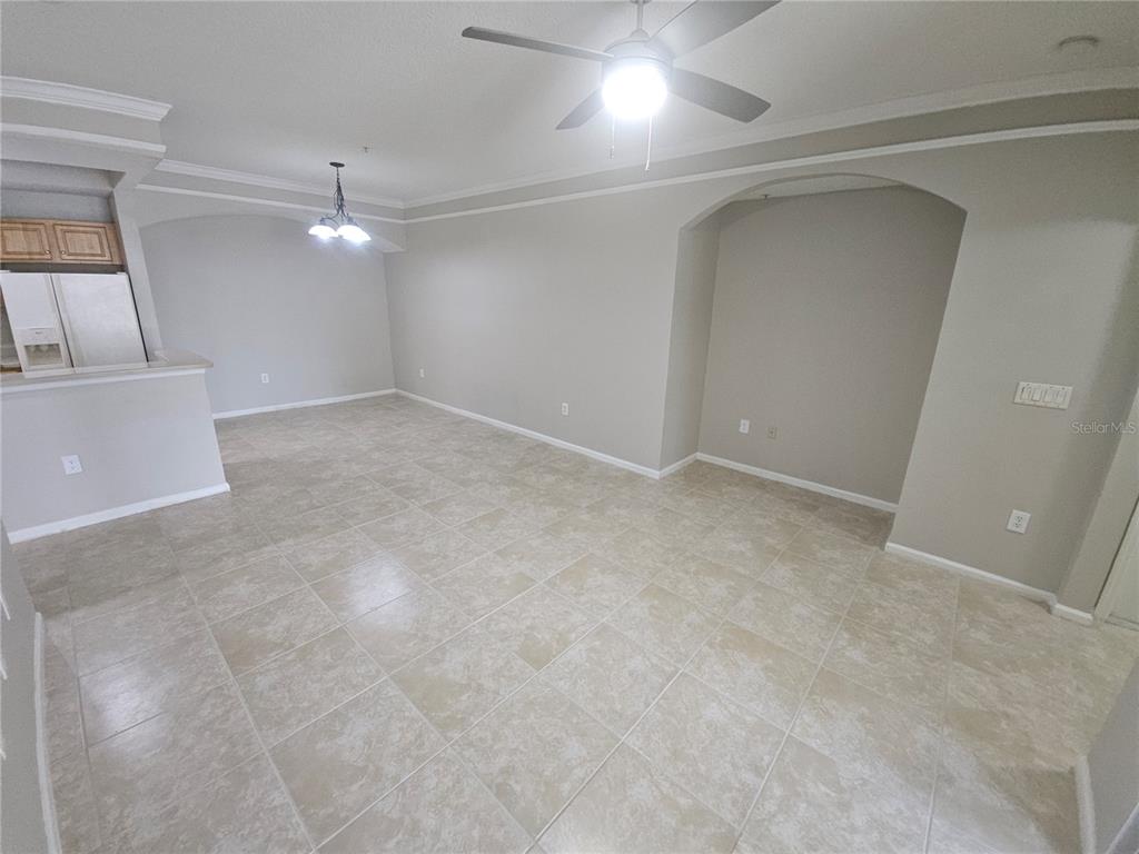 An open-concept living and dining area features beige tile flooring, neutral walls, and arched alcoves — 12024 VILLANOVA DRIVE UNIT 103, ORLANDO, FL