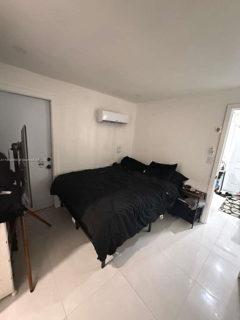 A bedroom features white walls, tile flooring, a black bed, and a wall-mounted air conditioner — 511 NW 133rd St # 4, North Miami FL 33168, NORTH MIAMI, FL