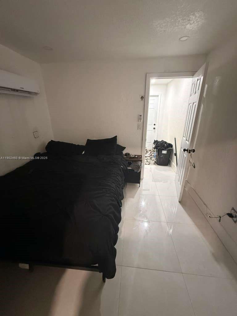 A bedroom with a bed, white tile flooring, and an open doorway to a hallway — 511 NW 133rd St # 4, North Miami FL 33168, NORTH MIAMI, FL
