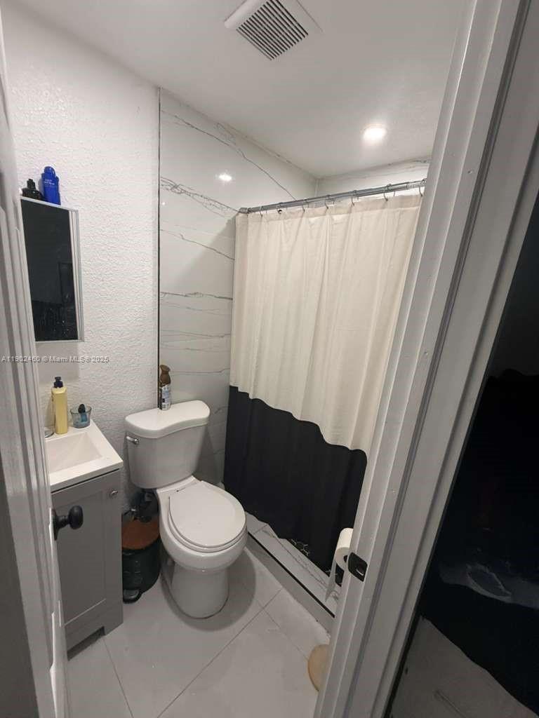 A small bathroom features a white vanity, a toilet, and a shower with a curtain — 511 NW 133rd St # 4, North Miami FL 33168, NORTH MIAMI, FL