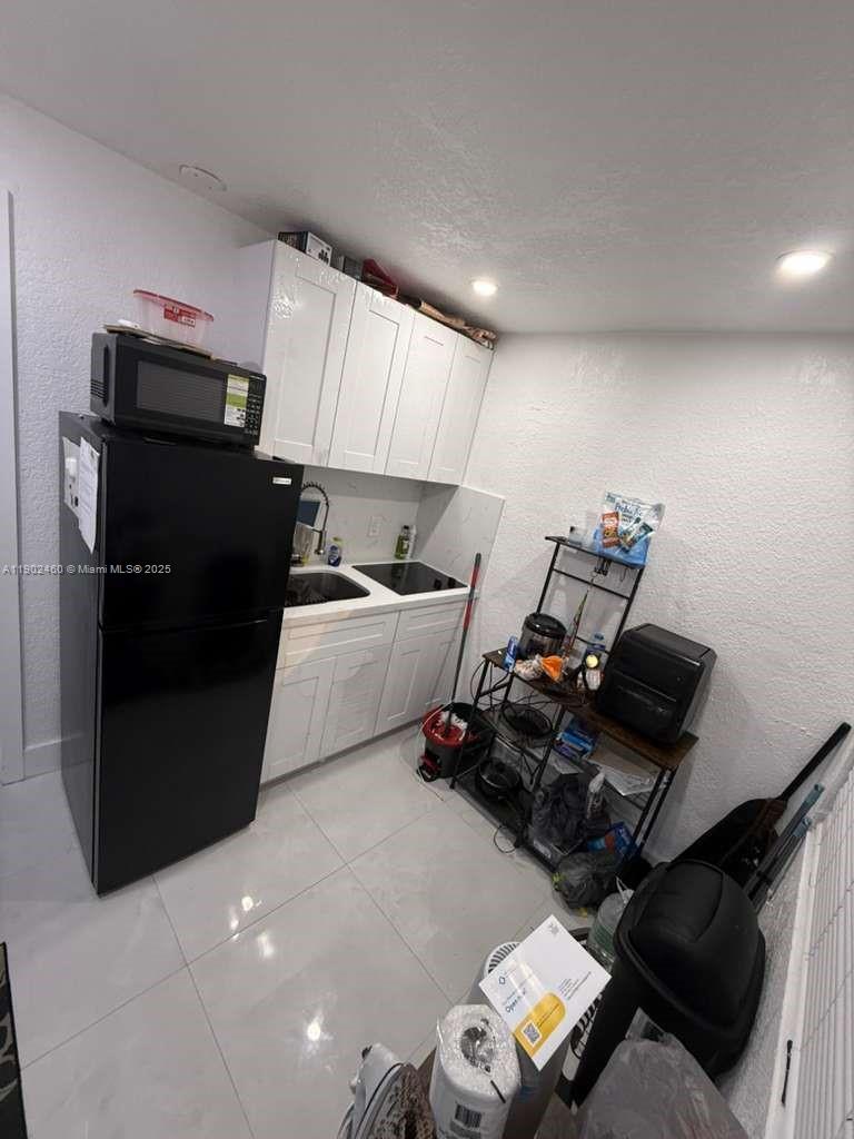 A small kitchen features white cabinets, a black refrigerator, and a metal shelving unit — 511 NW 133rd St # 4, North Miami FL 33168, NORTH MIAMI, FL