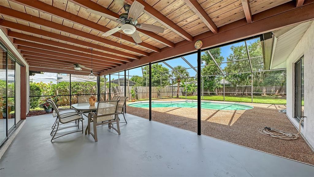 A covered patio with a dining set overlooks a screened-in swimming pool and backyard — 4736 CHARING CROSS ROAD, SARASOTA, FL