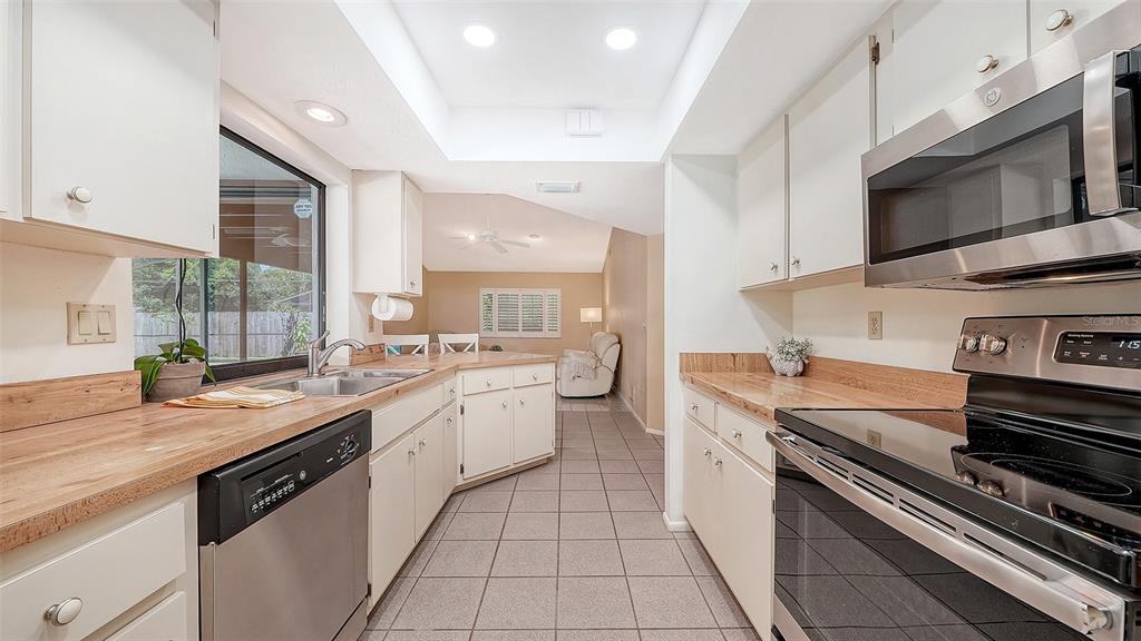 A kitchen with white cabinets, wood countertops, stainless steel appliances, and tile flooring — 4736 CHARING CROSS ROAD, SARASOTA, FL