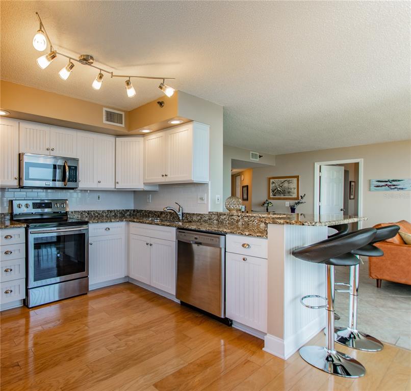 A kitchen features white cabinets, granite countertops, stainless steel appliances, and a breakfast bar — 6322 PALMA DEL MAR BOULEVARD S UNIT 1004, ST PETERSBURG, FL