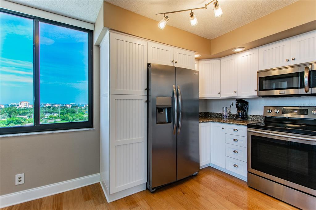 A kitchen with white beadboard cabinets, stainless steel appliances, and a large window with views — 6322 PALMA DEL MAR BOULEVARD S UNIT 1004, ST PETERSBURG, FL