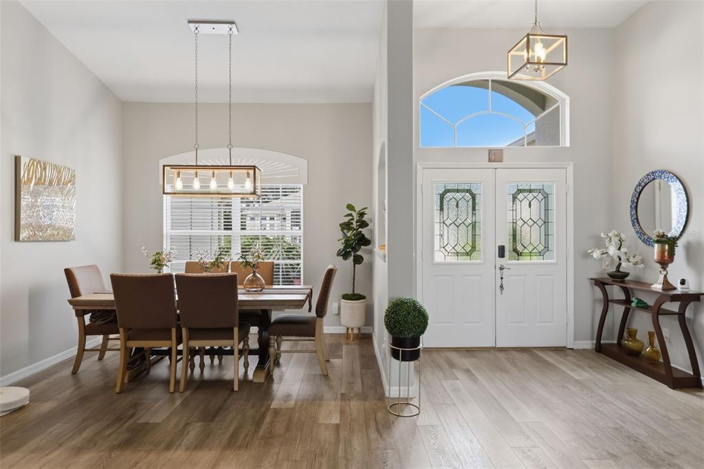 A dining area with a wooden table and chairs sits beside an entryway with double doors — 5519 AURORA DRIVE, LEESBURG, FL