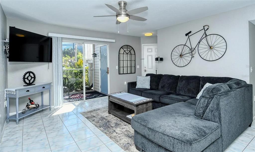 A living room features a dark sectional sofa, a coffee table, and a bicycle wall decoration — 850 S TAMIAMI TRAIL UNIT 801, SARASOTA, FL
