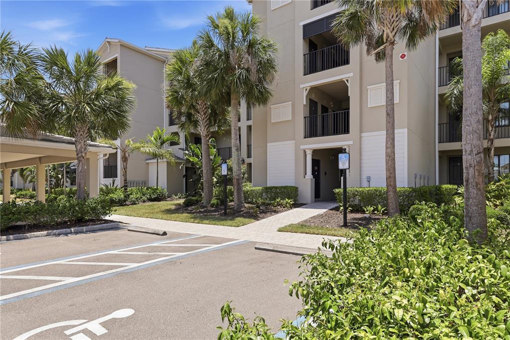 An exterior view of a multi-story apartment building with palm trees and a parking lot — 17902 GAWTHROP DRIVE UNIT 305, BRADENTON, FL