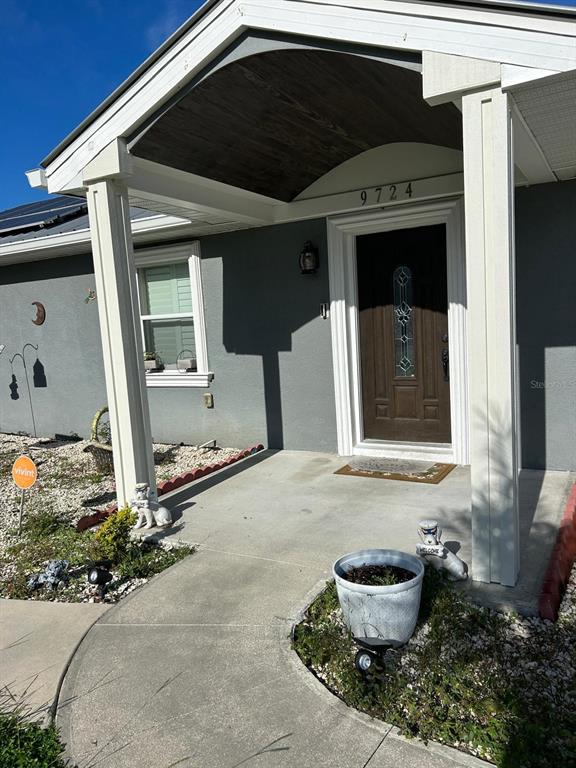 The exterior view shows a covered concrete porch with white columns and a dark door — 9724 TOM FOLSOM ROAD, THONOTOSASSA, FL