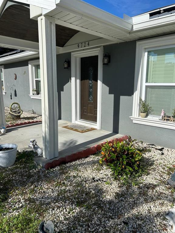 The exterior of a house features a covered porch, a brown front door, and gravel landscaping — 9724 TOM FOLSOM ROAD, THONOTOSASSA, FL