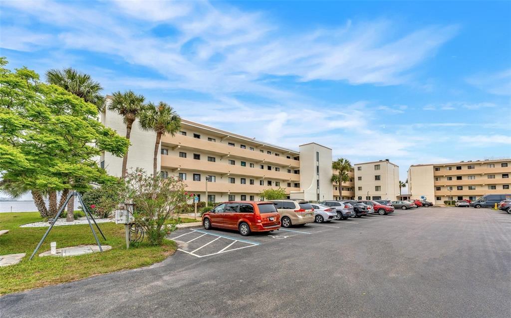 A multi-story apartment building with a parking lot in the foreground and palm trees — 2465 S WASHINGTON AVENUE UNIT A202, TITUSVILLE, FL