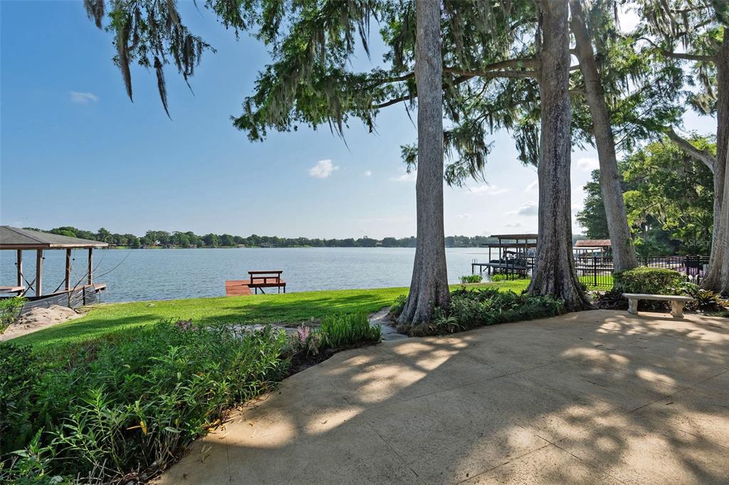 A paved patio overlooks a grassy lawn, a small wooden dock, and a large lake — 2655 LAKE SHORE DRIVE, ORLANDO, FL