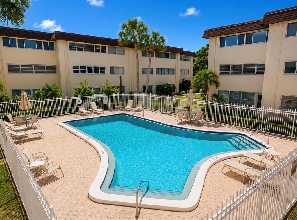 An outdoor swimming pool surrounded by lounge chairs and patio tables at a residential complex — 6360 1ST STREET N UNIT 103, ST PETERSBURG, FL