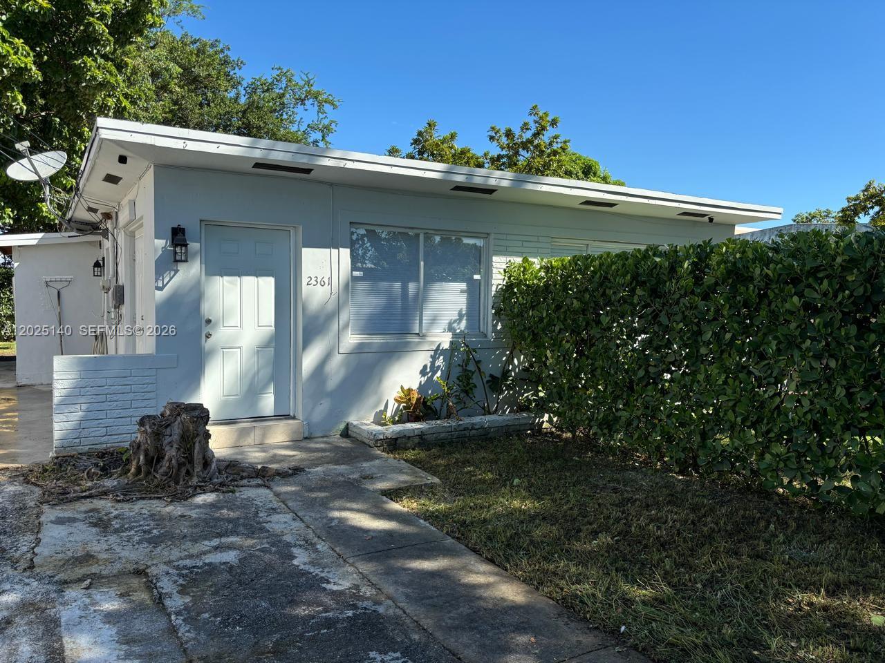 A light blue, single-story house features a flat roof, a front door, and a hedge — 2359 NW 32nd St, Miami FL 33142, MIAMI, FL