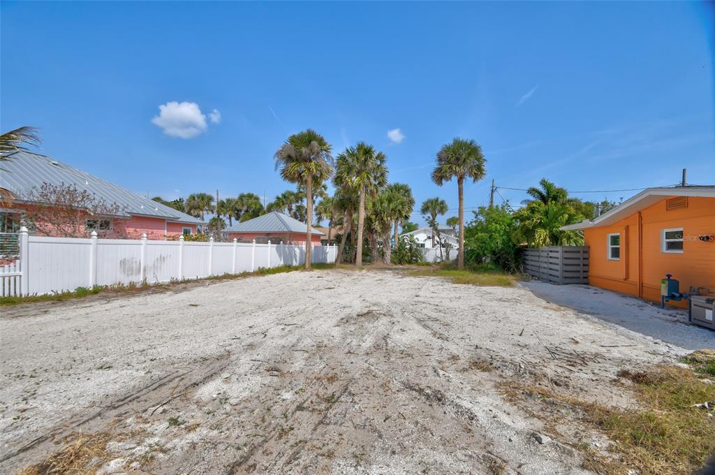 A vacant, sandy lot is bordered by a white fence, palm trees, and neighboring houses — 306 NORMANDY AVENUE, NEW SMYRNA BEACH, FL