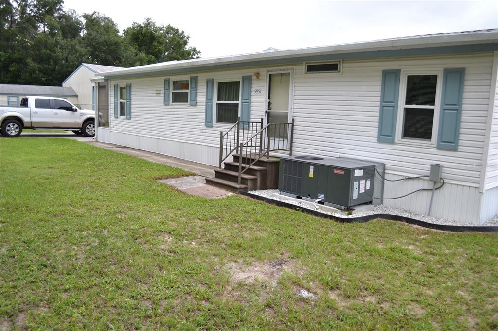 A white mobile home with blue shutters sits on a grassy lot with a concrete walkway — 5951 SE 158TH COURT, OCKLAWAHA, FL
