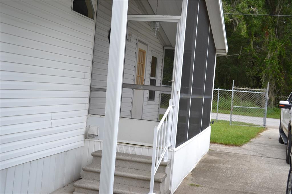 The exterior side of a manufactured home features white siding, a window, and an HVAC unit — 5951 SE 158TH COURT, OCKLAWAHA, FL