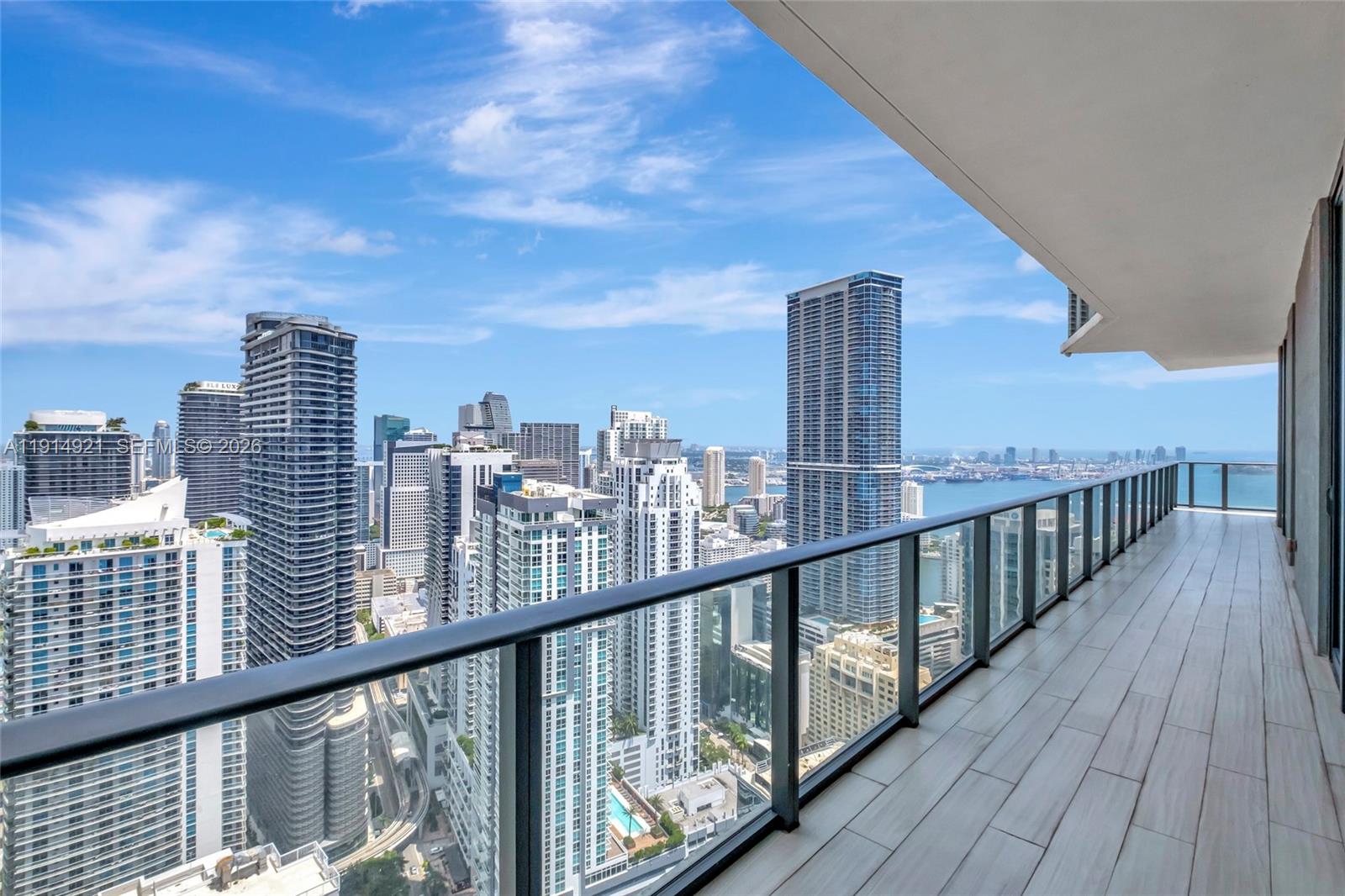 A high-rise balcony with a glass railing overlooks a dense city skyline and the ocean — 1300 S Miami Ave, Miami FL 33130, MIAMI, FL